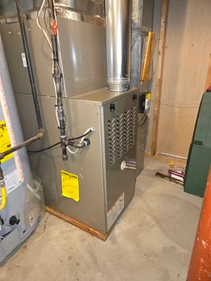 Newly installed gas furnace with ductwork connections and yellow safety labels