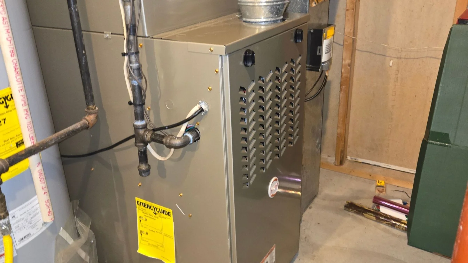 New gas furnace installation with ductwork, piping, and electrical connections in basement